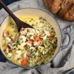 Looking down on a pot of Creamy Seafood Chowder with a loaf of brown in the background.