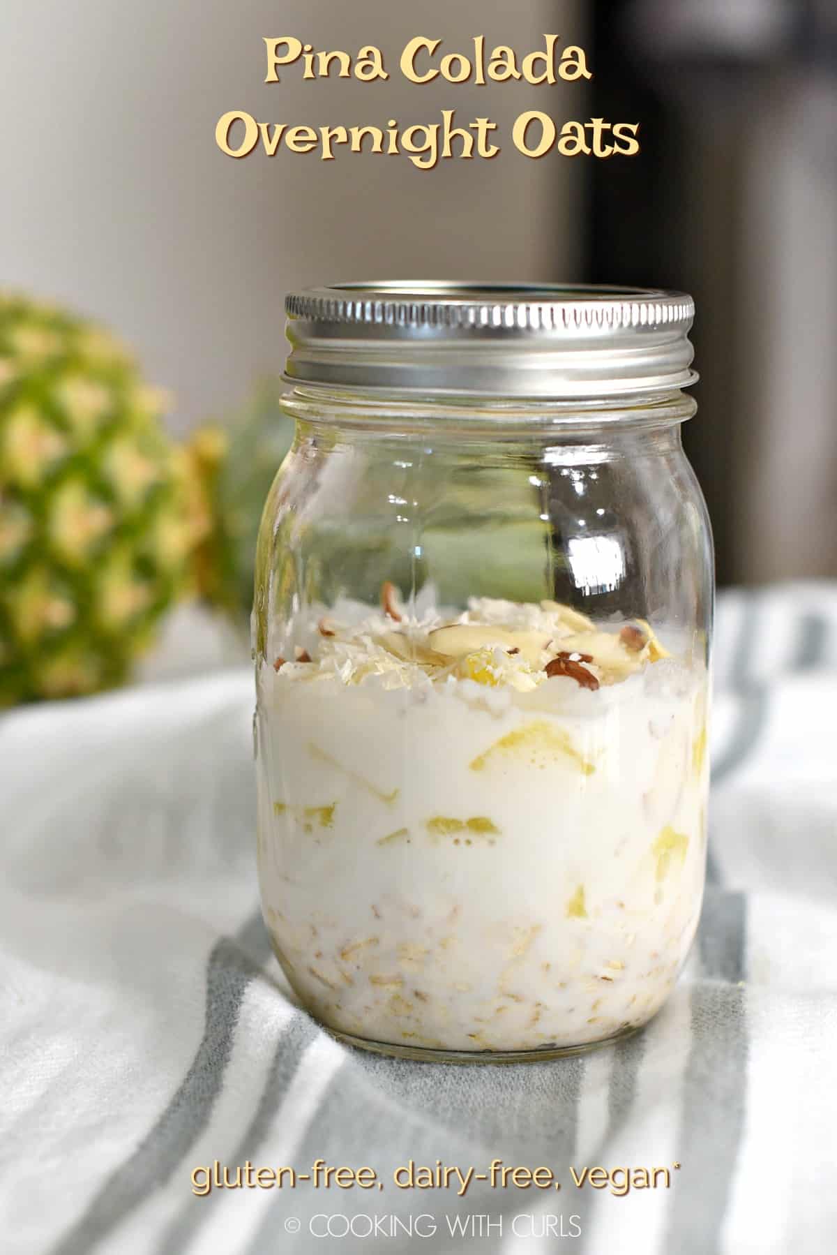 Side view of a glass mason jar layered with Pina Colada Overnight Oats. Title graphic across the top of image and nutrition information across the bottom.