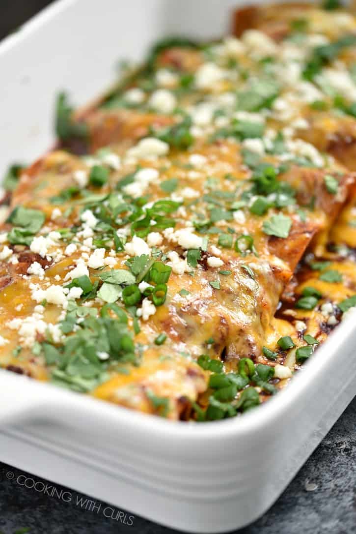 Close-up image of chicken enchiladas topped with red sauce and melted cheeses.