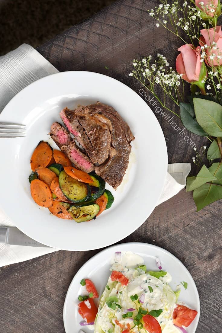 Looking down on a Ribeye Steak served with a Wedge Salad and Sauteed Zucchini and Carrots.