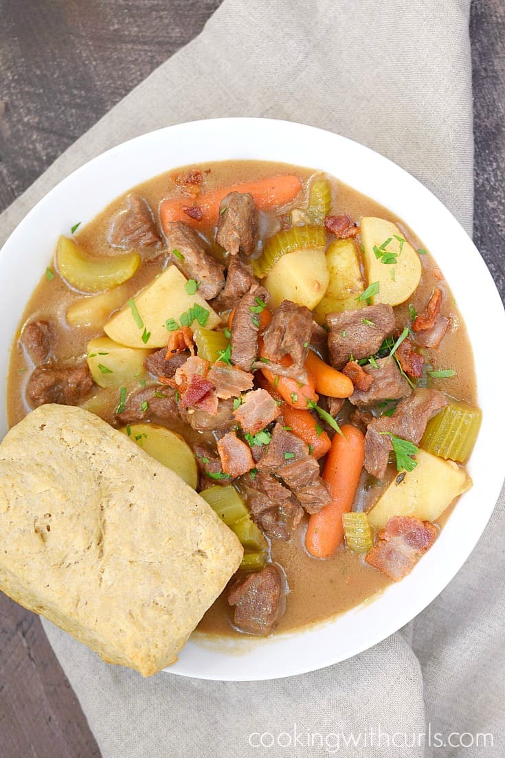 A shot from above of a big white bowl of Beef Stew with Guinness Biscuits sitting on a beige napkin