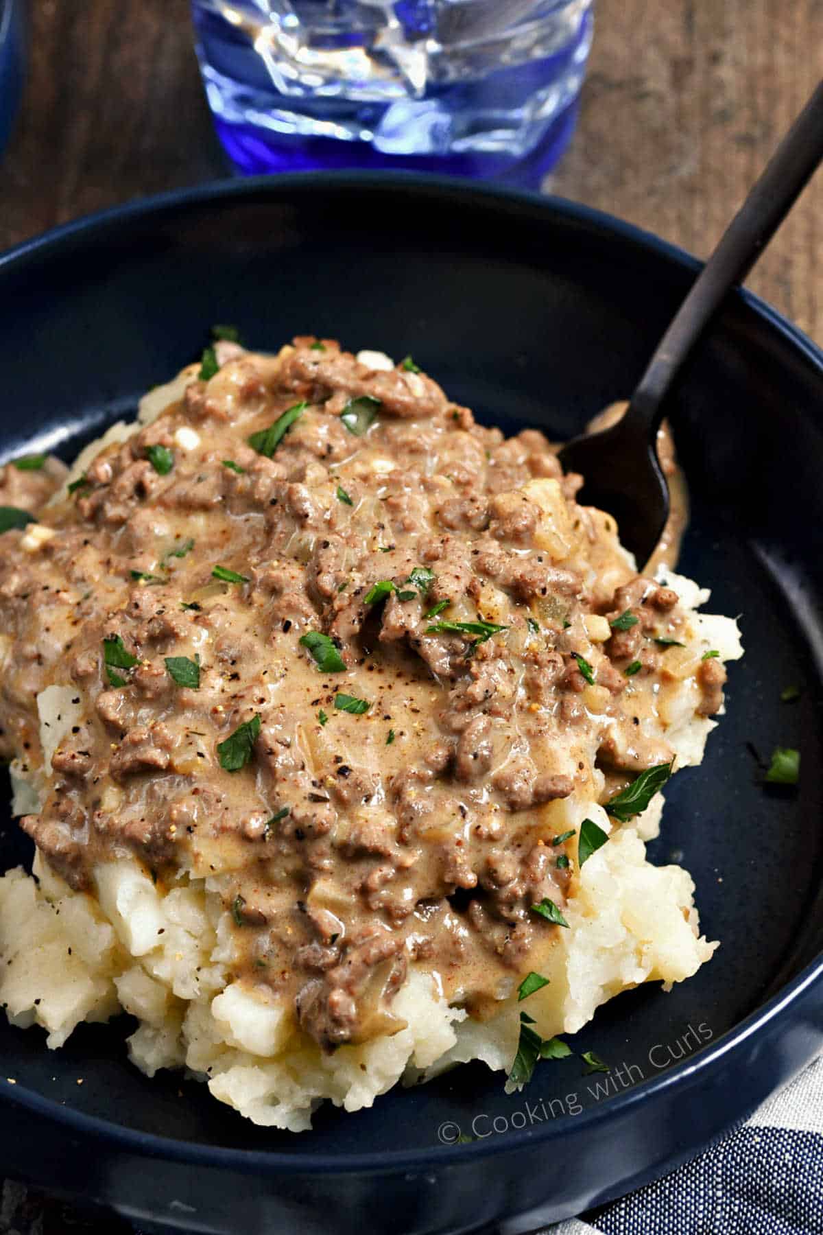 A-bowl-of-mashed-potatoes-topped-with-Hamburger-Gravy-and-chopped-parsley.