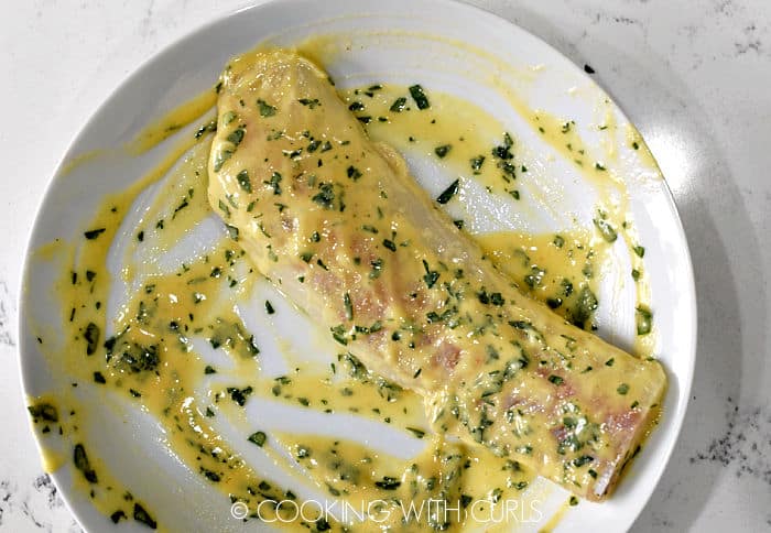 A piece of cod coated in the mustard mixture on a white plate. 