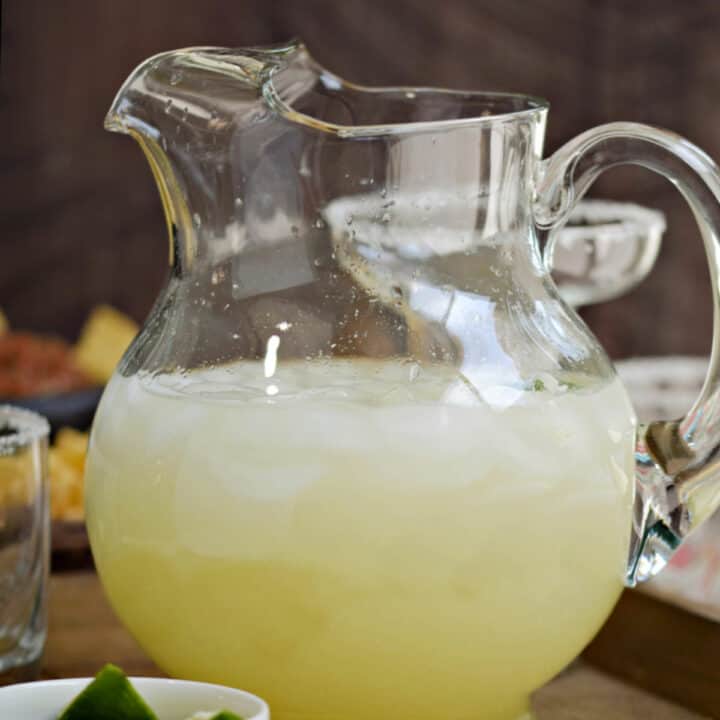 A pitcher of margaritas with ice cubes.