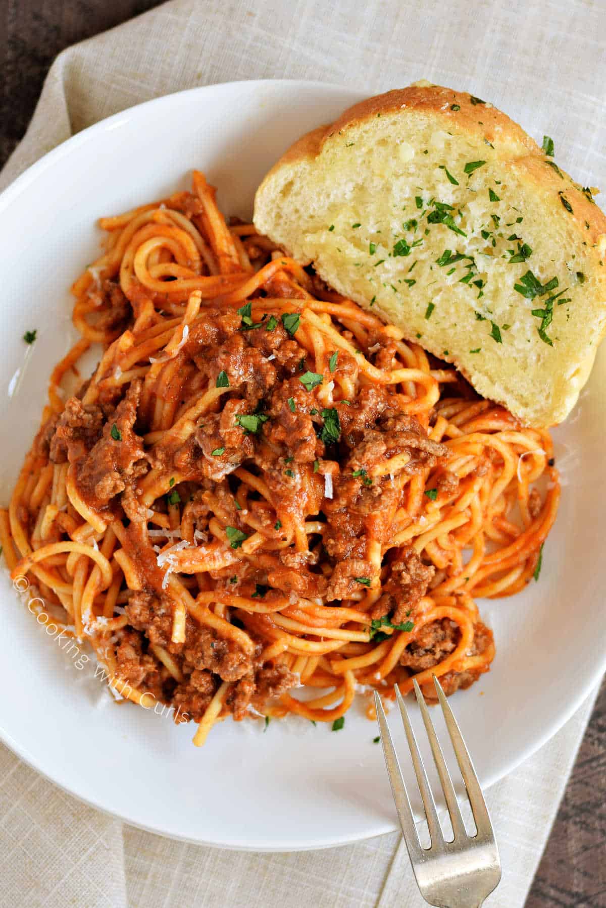 Looking down on a plate of Instant Pot Spaghetti with meat sauce and garlic bread on the side.