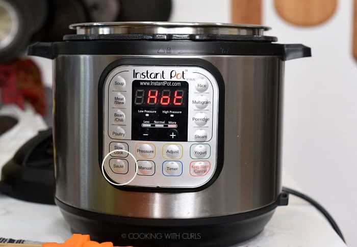 A pressure cooker set to Saute and HOT on the display