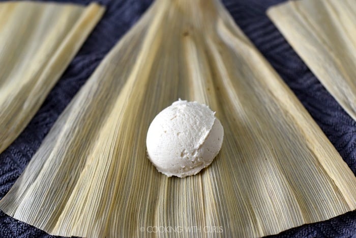 A scoop of masa mixture in the center of a corn husk. 