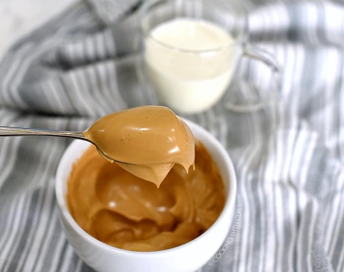 A scoop of the whipped coffee mixture on a large spoon hovering over a white bowl. 