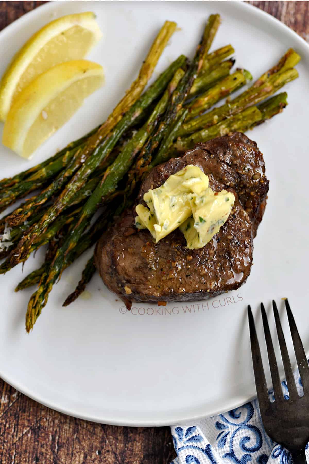 Air Fryer Steak and Asparagus topped with garlic butter on a white plate.