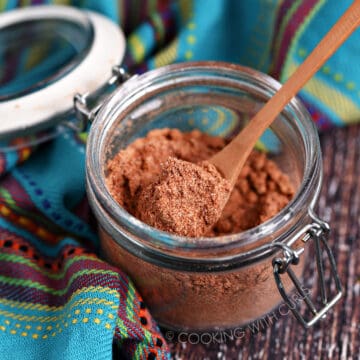 Mexican Seasoning Recipe in a small glass jar with a wooden spoon.