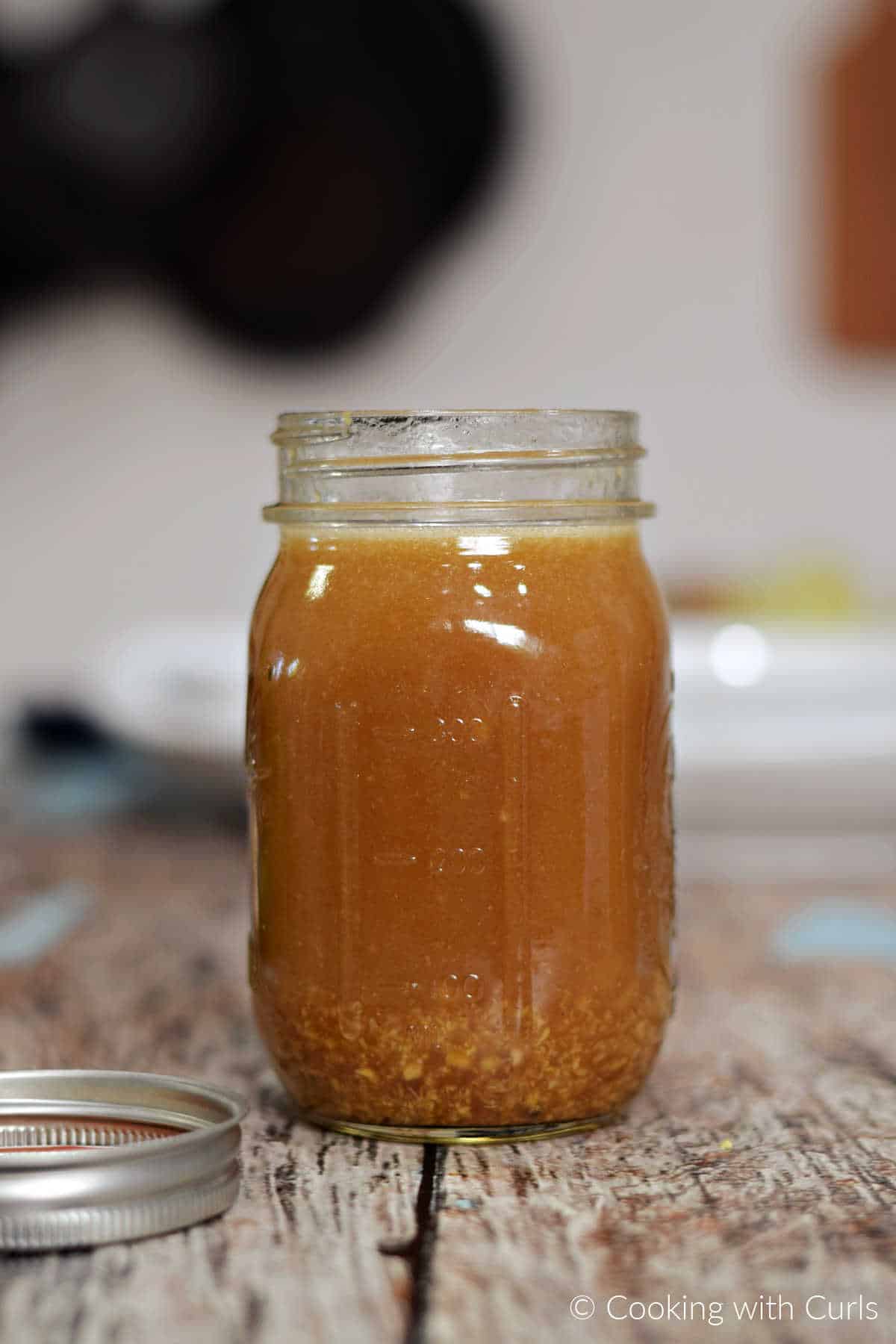 Shaken Asian orange sesame ginger dressing in a glass mason jar.