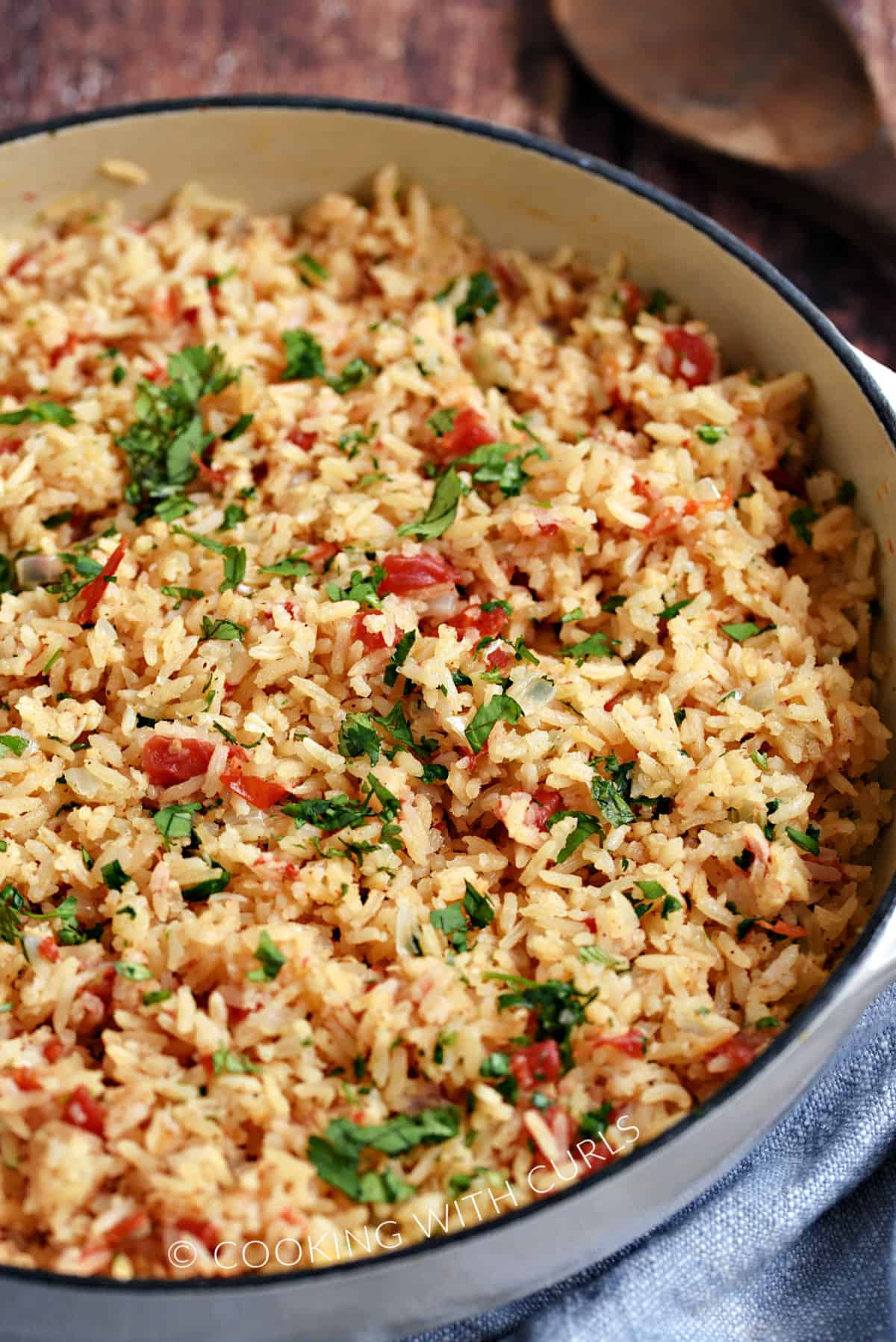 Rice, tomatoes, onions and cilantro in a large, white skillet.
