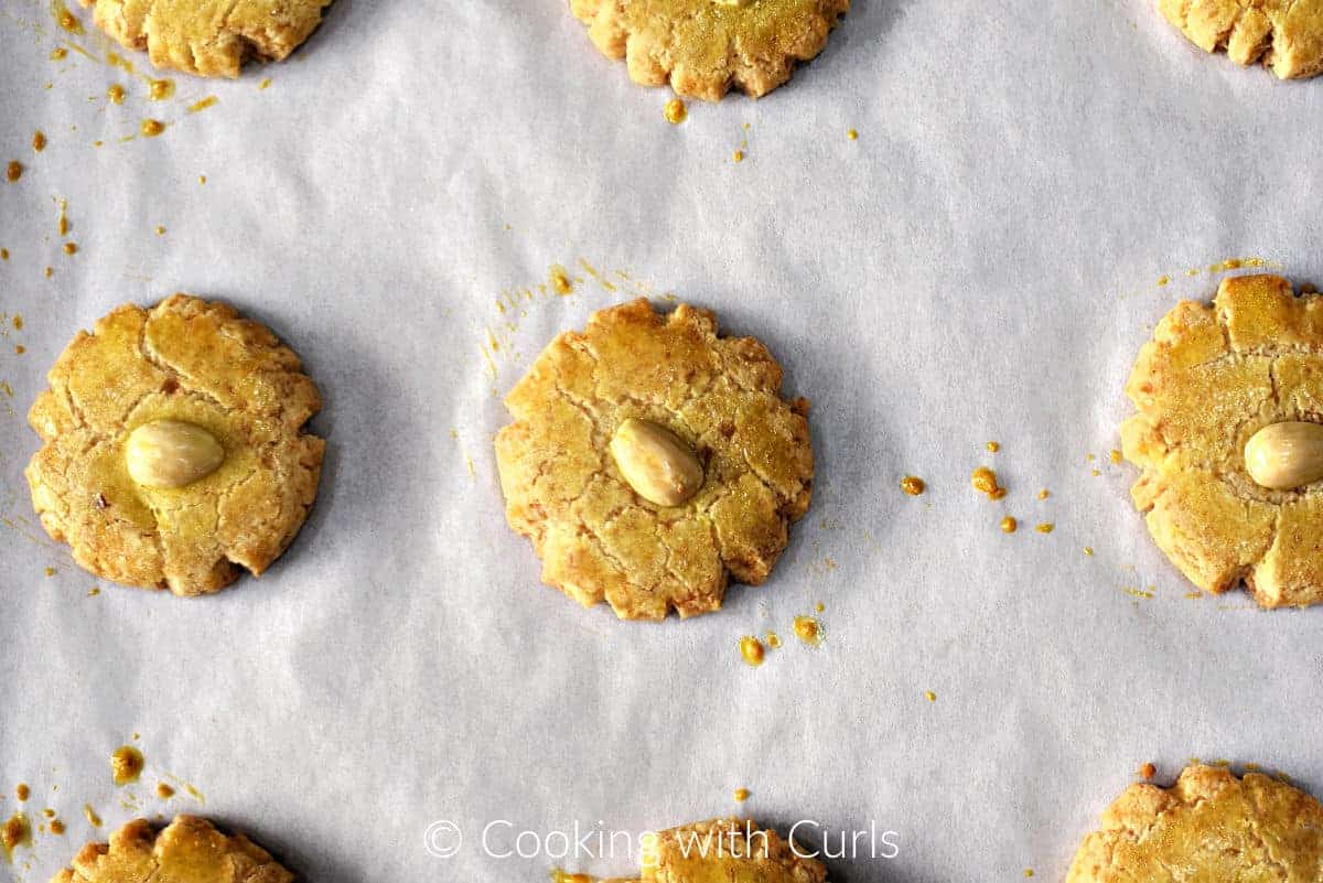 Baked almond cookies on a parchment lined baking sheet. 