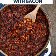 Looking down on a skillet of baked beans with bacon wrapped in a dark blue napkin with white stars and a wooden spoon and title graphic across the top.