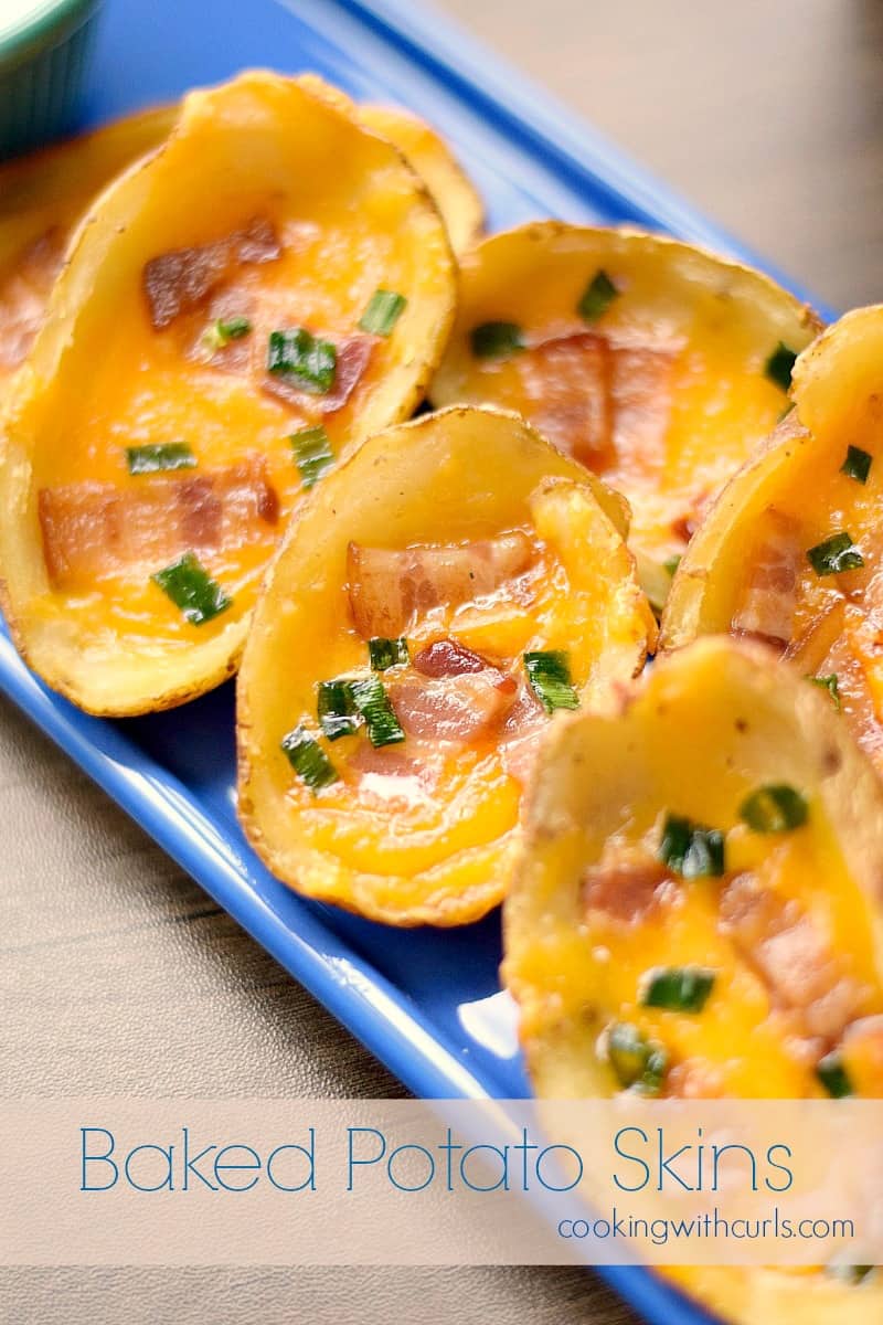 potato skins topped with bacon and green onions spread out on a rectangle blue plate