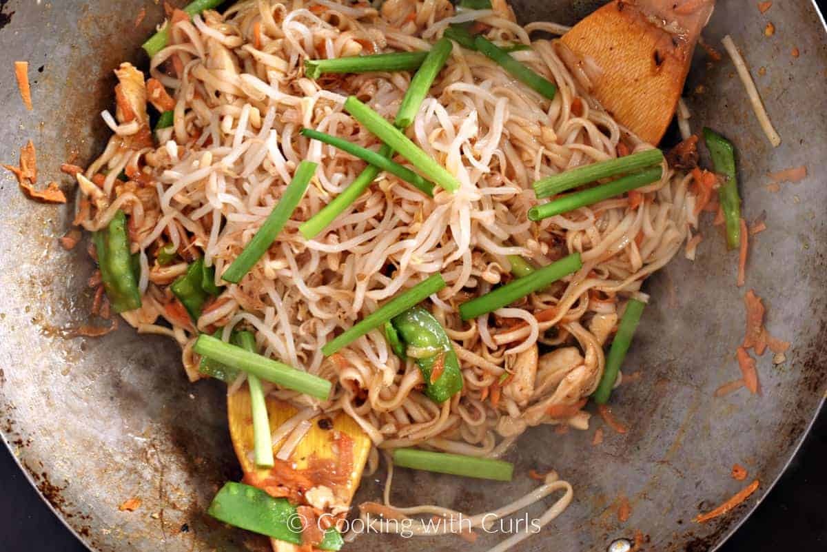 Bean sprouts, green onion tops, and noodles added to the wok. 