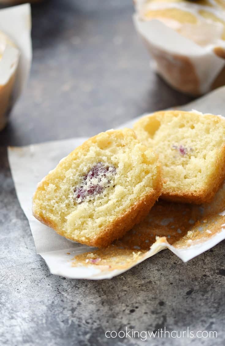 A muffin split in half with a blackberry in the center.