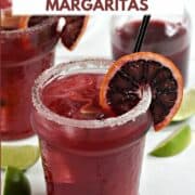 Two blood orange margaritas in short glasses garnished with an orange wheel and a sugar rim with title graphic across the top.