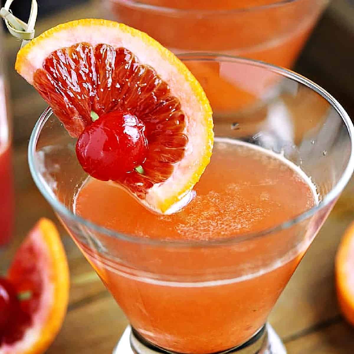 Blood Orange Martini with a slice of blood orange and a cherry garnish on a bamboo skewer.