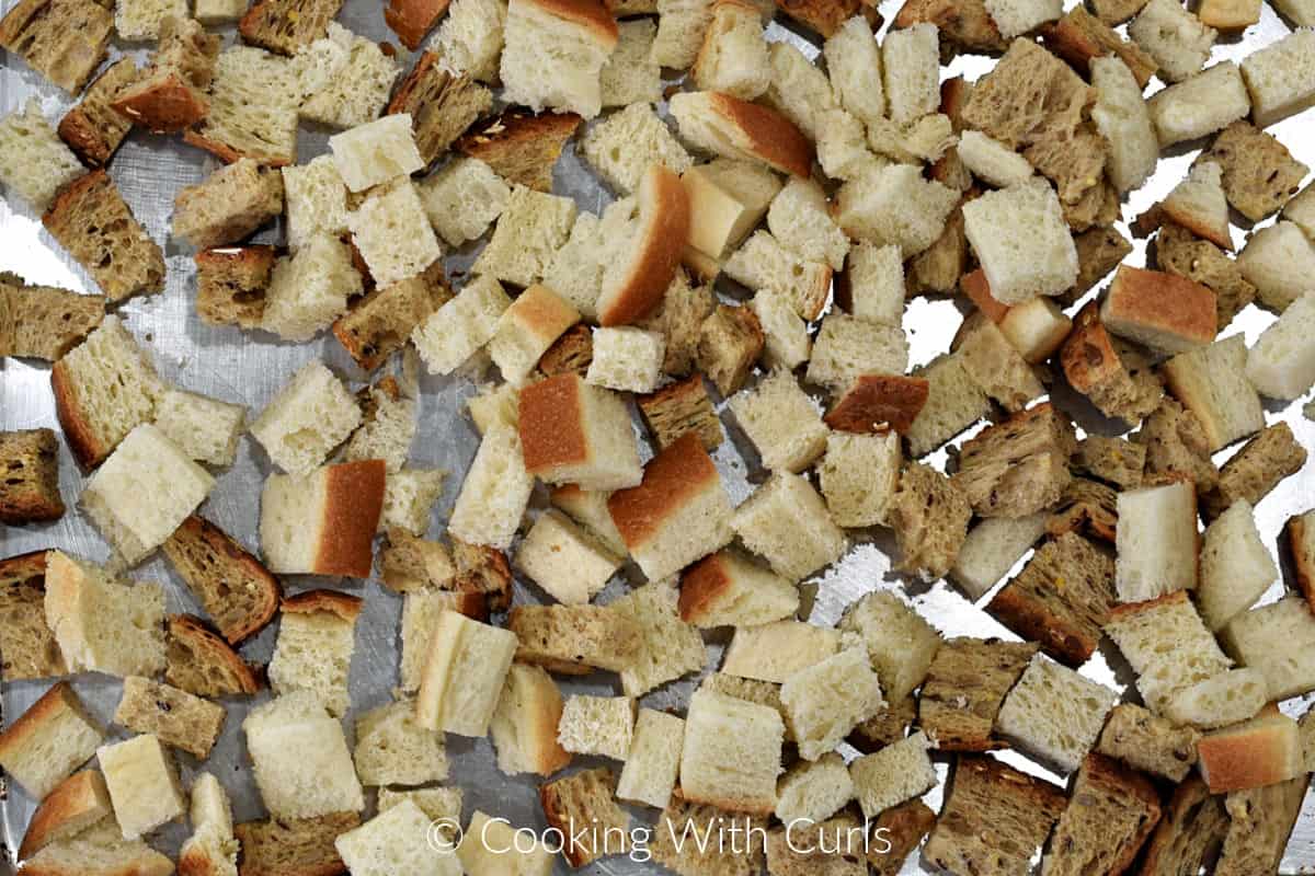 Bread cubes spread out on a baking sheet. 