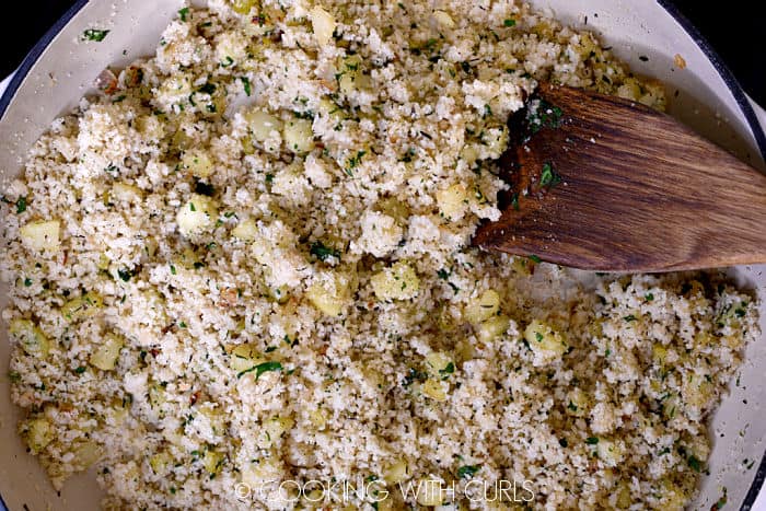 Breadcrumbs stirred into the mixture in the skillet with a wooden turner.