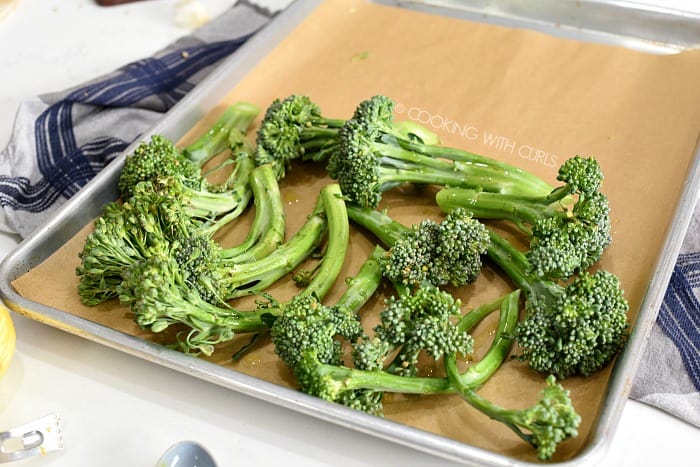 Broccolini placed on half of a parchment paper lined baking sheet 