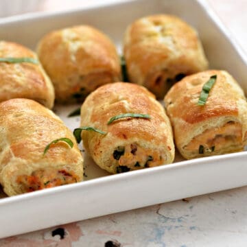 Crispy puff pastry filled with bruschetta chicken sausage rolls lined up on a serving tray.