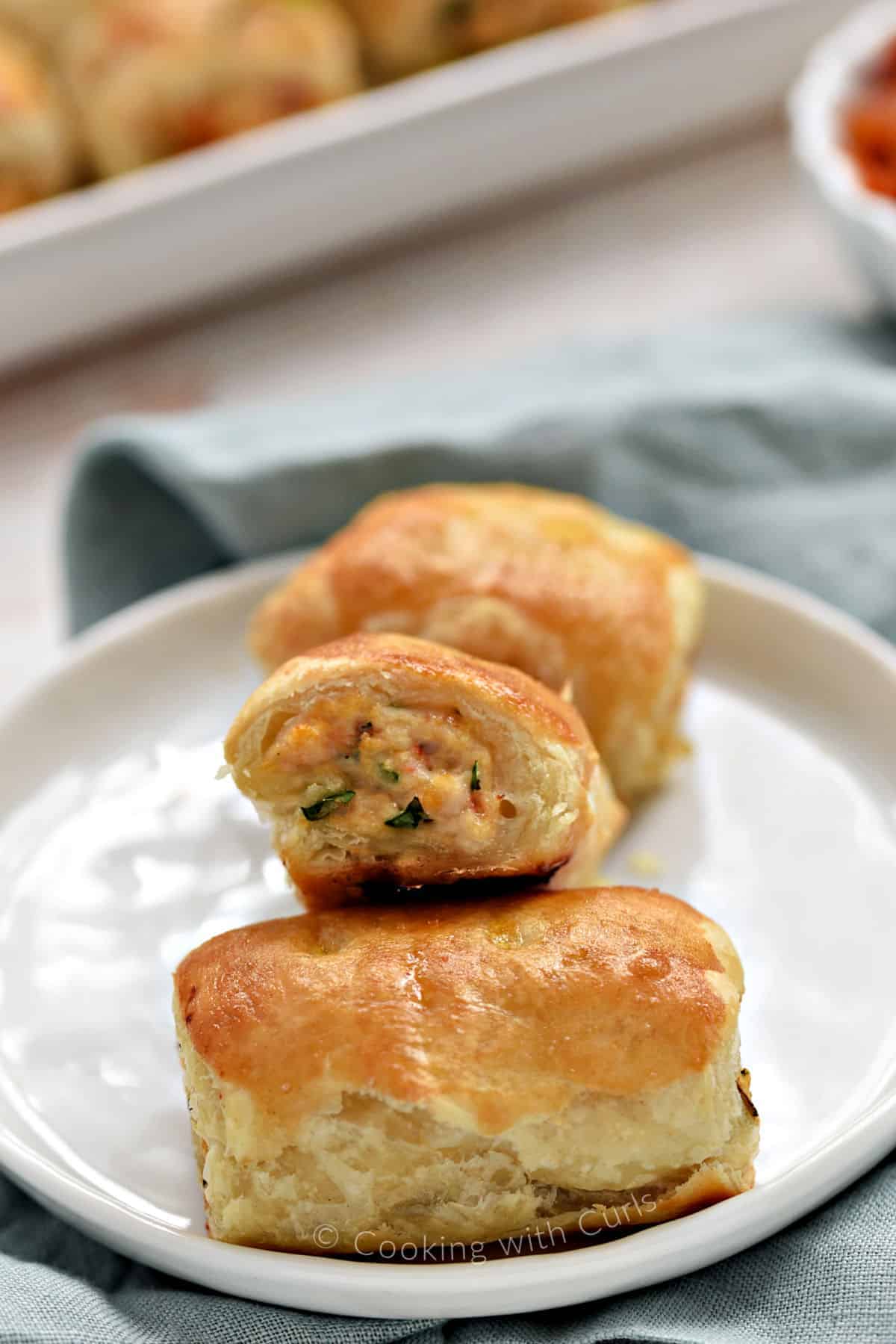 Three chicken sausage rolls stacked on a small plate to show the filling.