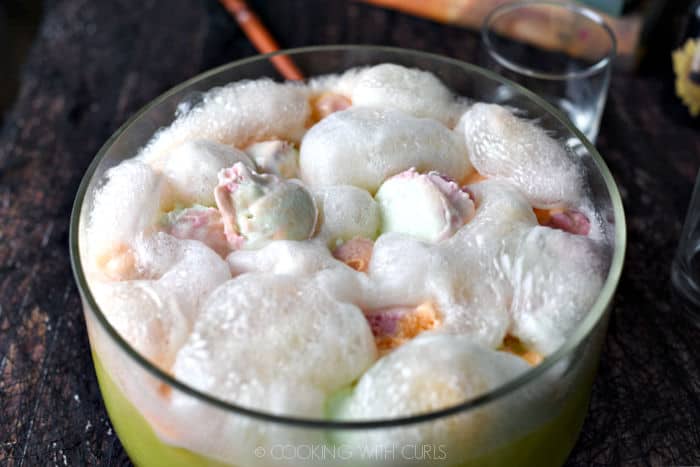 bubbling, foaming polyjuice potion cocktail with rainbow sherbet, lemon-lime soda and vodka in a glass punch bowl. 