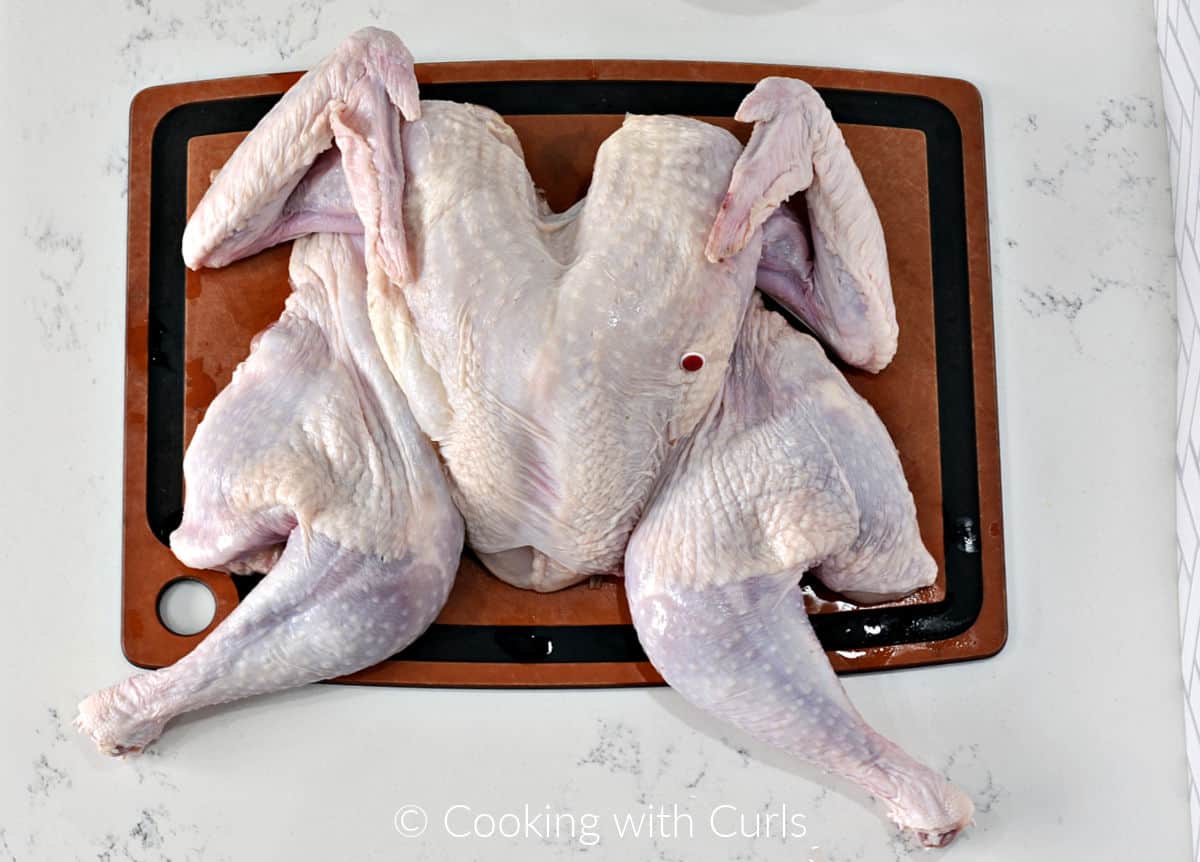 Butterflied turkey laying on a cutting board. 