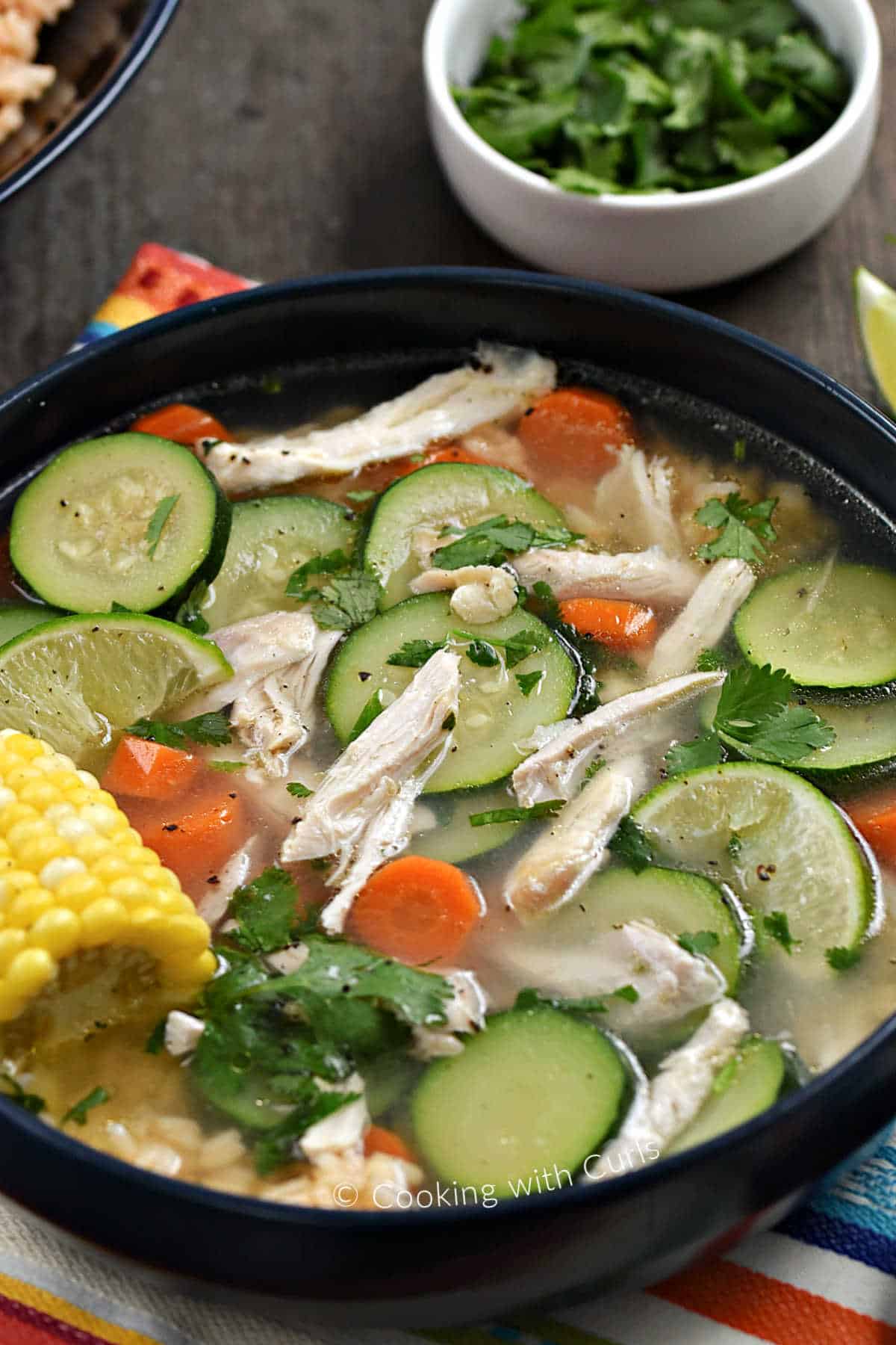 Chicken, sliced zucchini, carrots, and corn on the cob in a bowl.