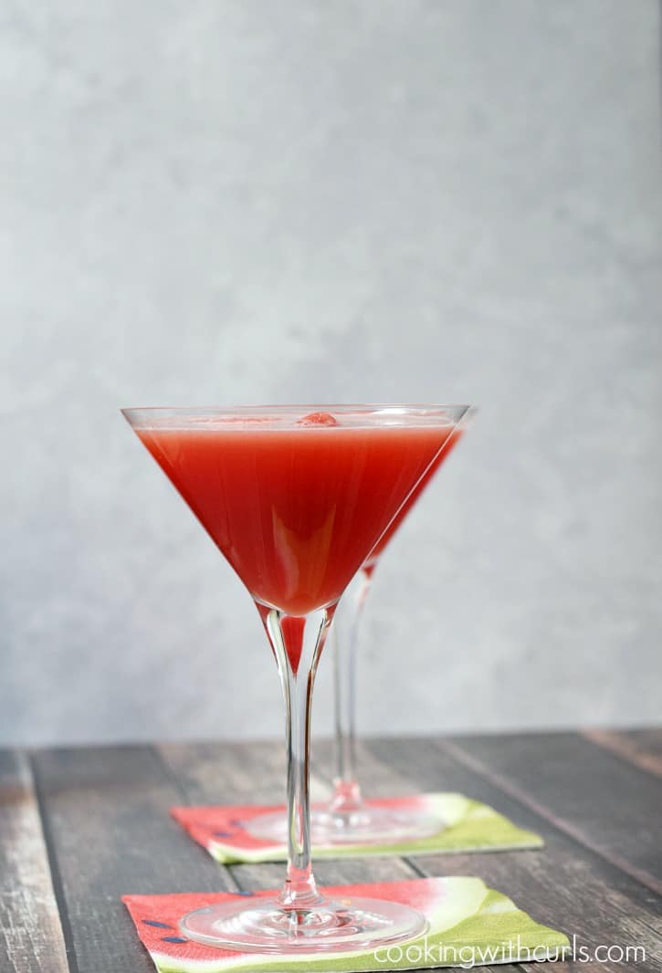 Two martini glasses filled with a slushy watermelon cocktail with a watermelon ball floating on top.