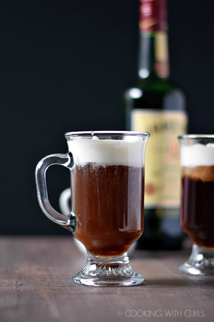 side view of two Irish Coffees with a bottle of Jameson in the background