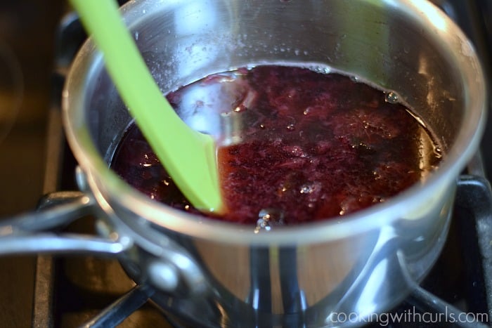 Green potato masher squishing the cherries in the syrup.