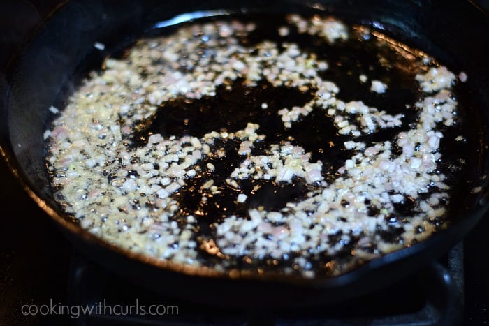 Shallots simmering in a cast iron skillet.