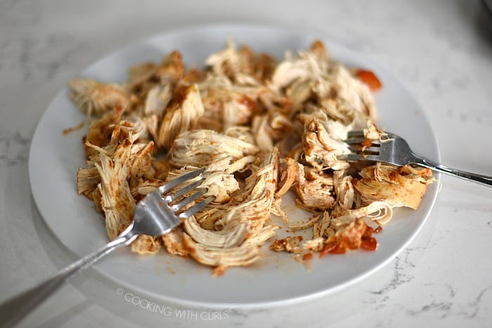 Chicken breasts shredded on a plate with two forks cookingwithcurls.com