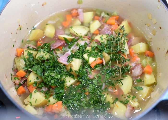 Chicken stock, parsley and thyme added to the vegetables in a large pan. 