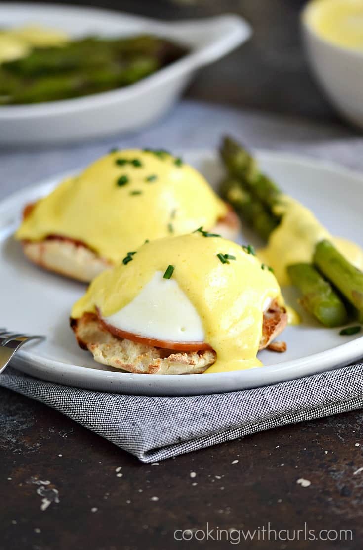 Two Eggs Benedict on a plate with asparagus spears.