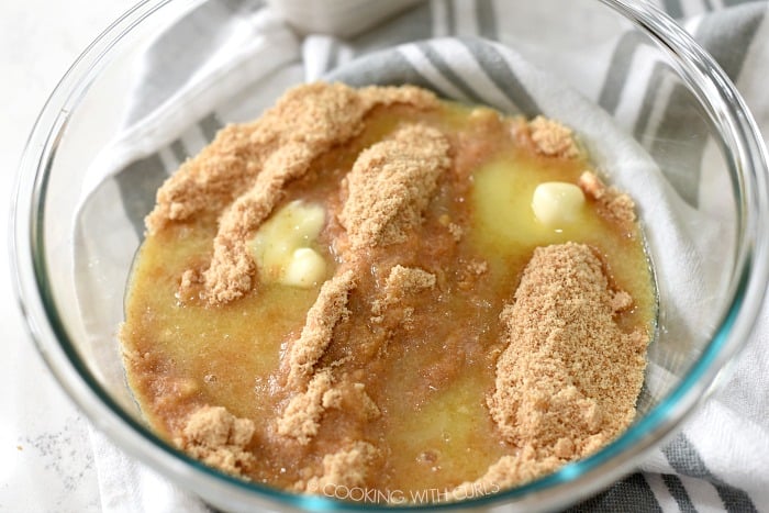 Cookie crumbs and melted butter in a clear glass bowl. 