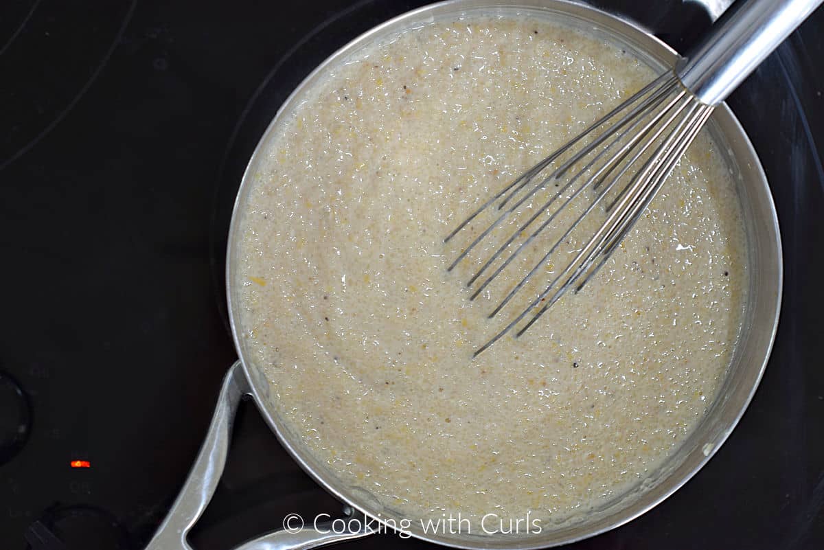 Corn grits whisked into milk and broth in a saucepan.