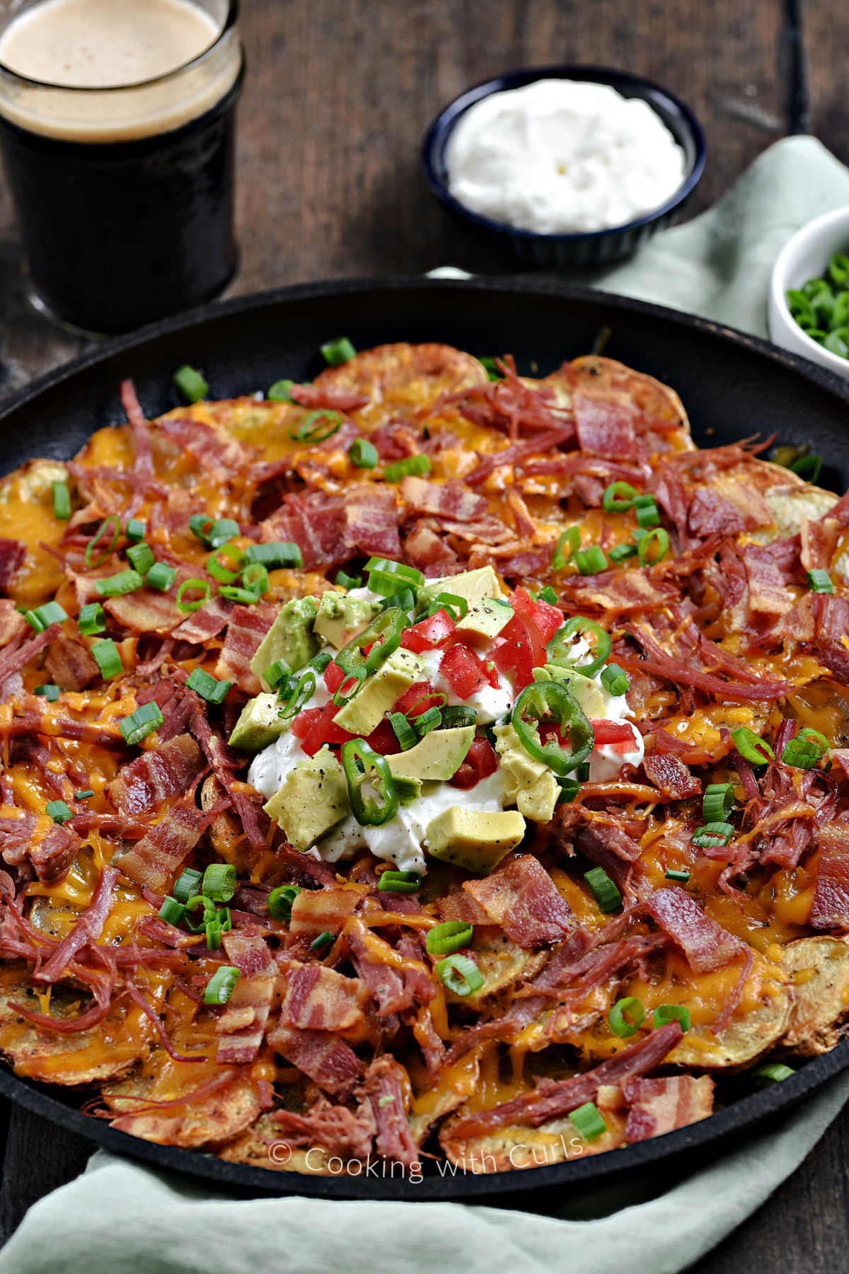 Corned Beef Irish Nachos with potato slices, melted cheddar cheese, corned beef, bacon, green onions, sour cream, diced tomatoes and avocado chunks.