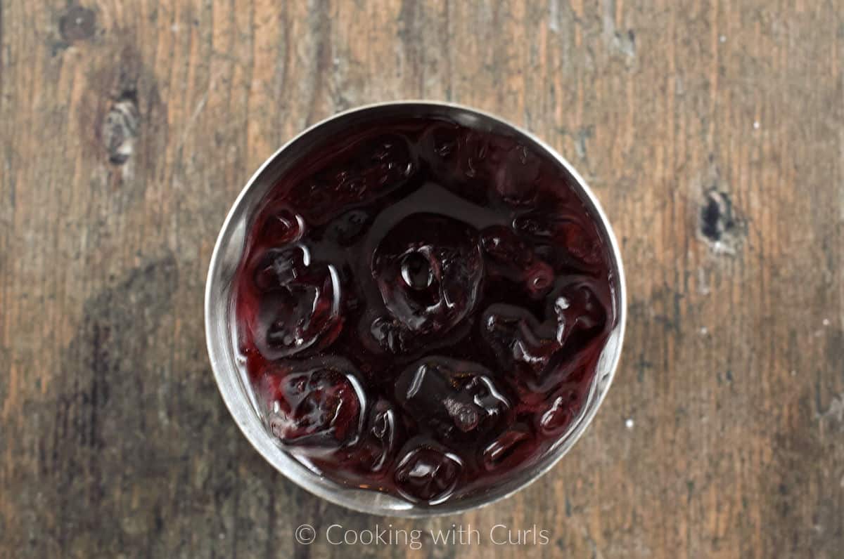 Cranberry juice, vodka, and ice cubes in a cocktail shaker. 