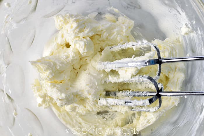 Cream cheese and sugar beaten with a hand mixer in a glass bowl. 