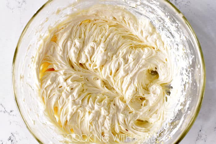 Cream cheese, yogurt and lemon mixed together in a glass bowl. 