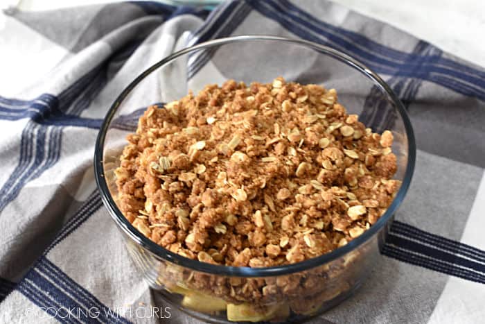 crisp topping on top of the chopped apples in a glass bowl. 