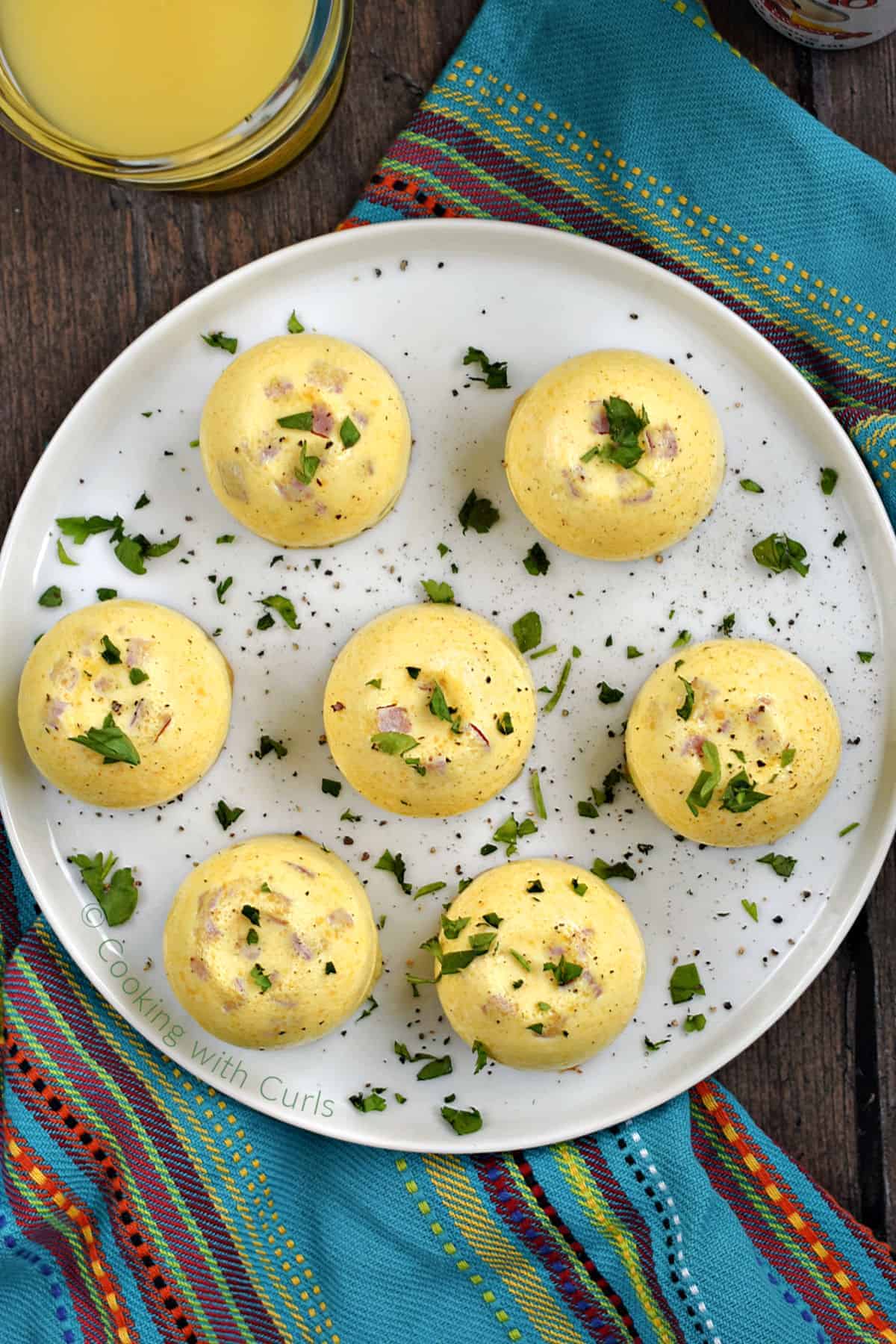 Looking down on sevenDenver Omelet Egg Bites on a plate with a glass of orange juice in the background.