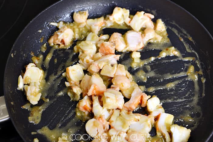 Diced lobster tossed with the lemon-garlic sauce in the skillet. 