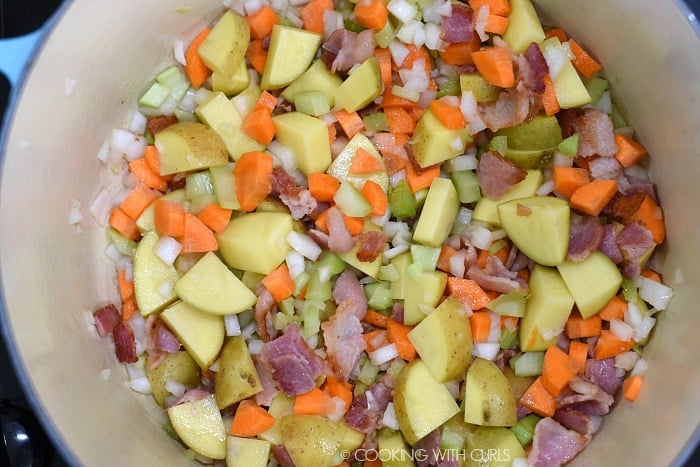 Diced onions, celery, carrots and potatoes added to the cooked bacon in a large pan. 