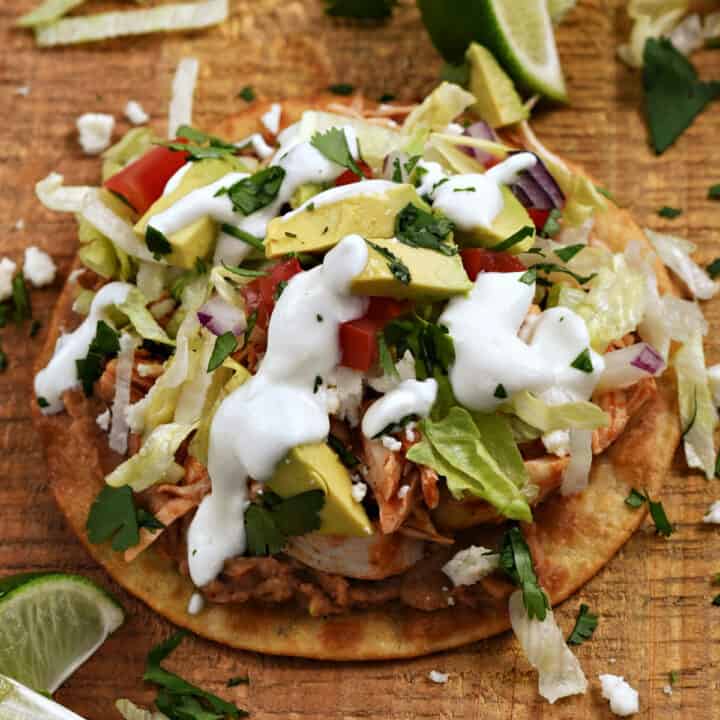 Crispy corn tortilla shell topped with beans, chicken, tomato, avocado, lettuce, and sour cream.