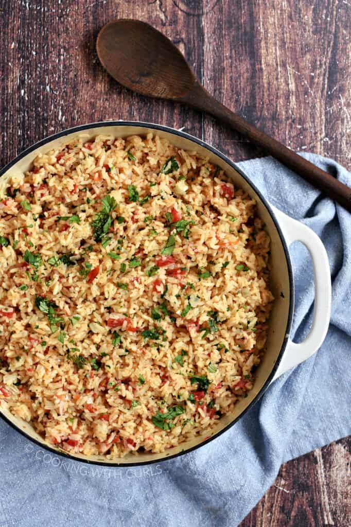 Looking down on Mexican rice in a white cast iron skillet.